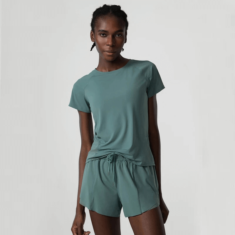 Woman wearing breathable nylon gym wear for yoga and running, featuring a short-sleeve top and shorts in solid teal, design SF2081.