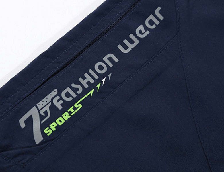Close-up of breathable quick dry men's long shorts with zipper pocket detail, featuring "7 Fashion Wear Sports" branding. Model SF1353.
