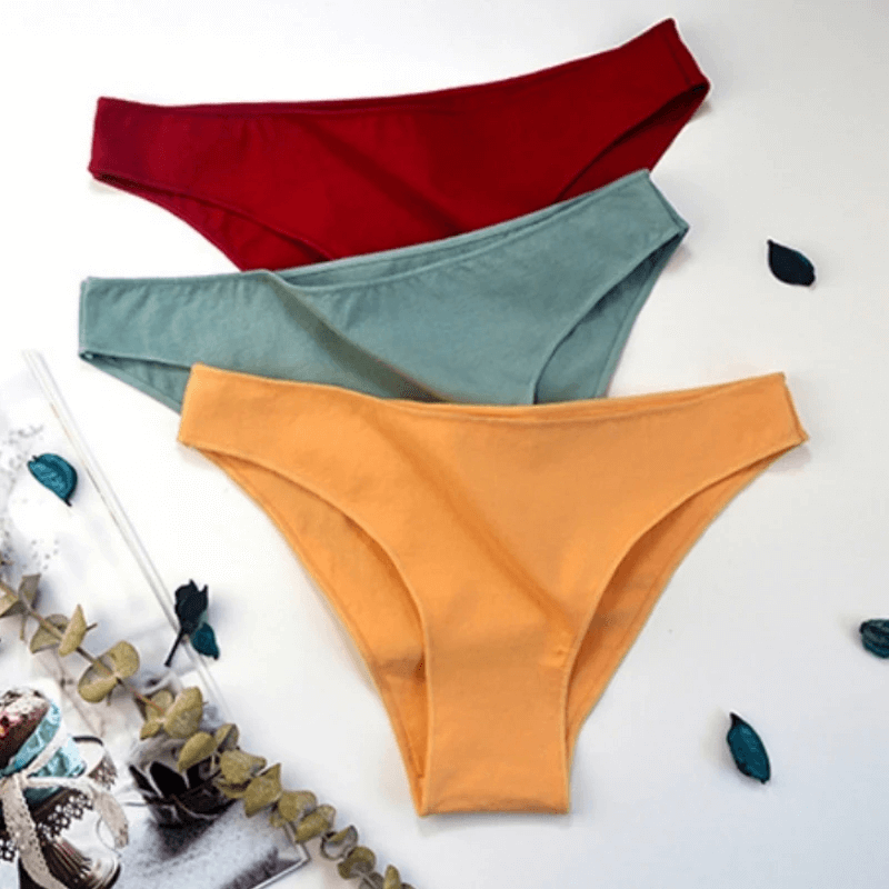 Three pairs of breathable women's low-rise cotton briefs in red, green, and yellow, showcasing a soft and sleek design for everyday wear.