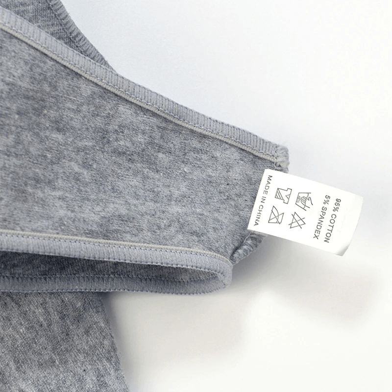 Close-up of grey women's cotton low-rise briefs with label showing care instructions and fabric composition.