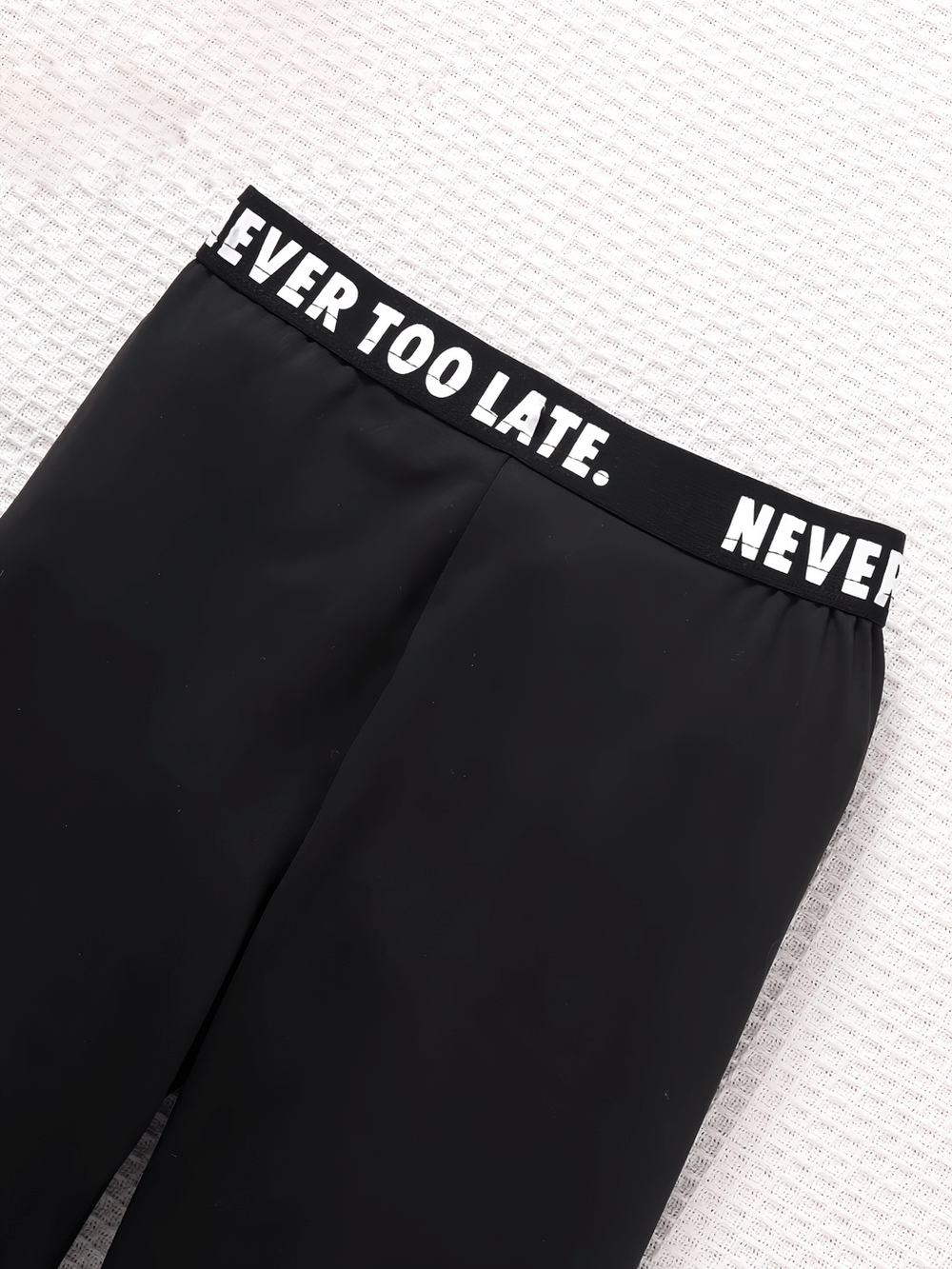 Close-up of sporty leggings with "Never Too Late" elastic waistband emphasizing motivation in activewear