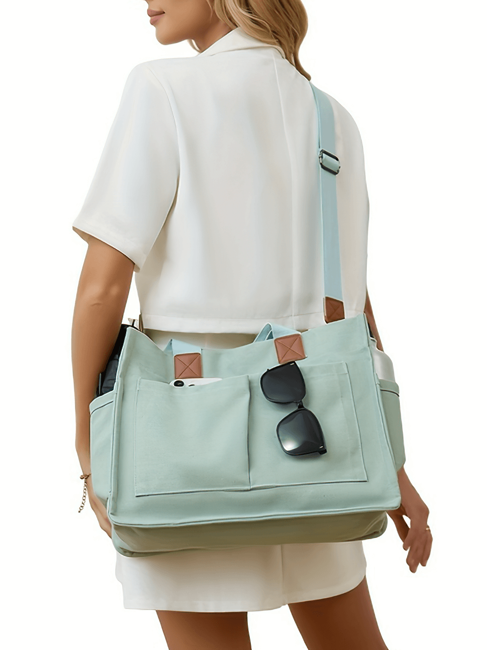 Woman carrying a large-capacity canvas tote bag with adjustable strap, featuring pockets for essentials and a secure buckle closure.