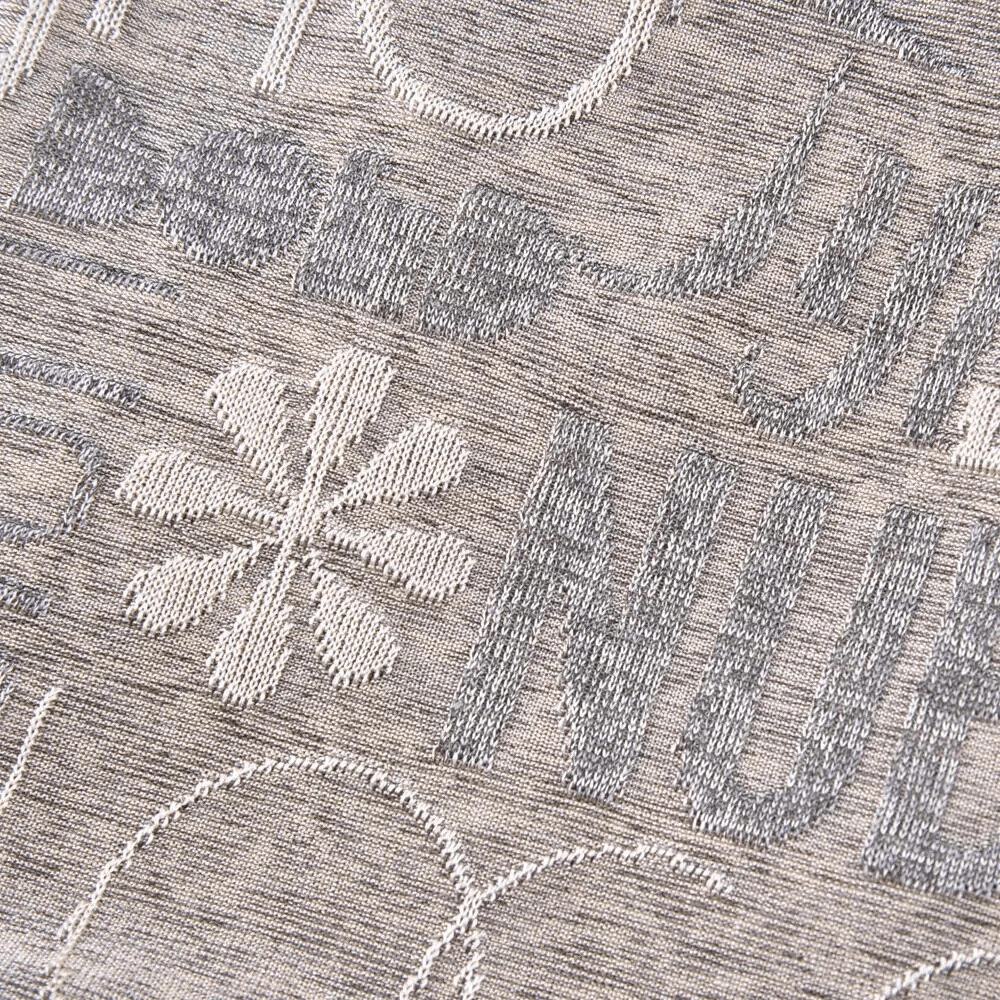 Close-up of a knitted fabric with letter and flower pattern in grey and white, part of a unisex casual scarf-hat.