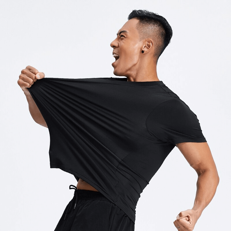 Man wearing a black quick-dry sport t-shirt with reflective stripes, stretching shirt for comfort demonstration.