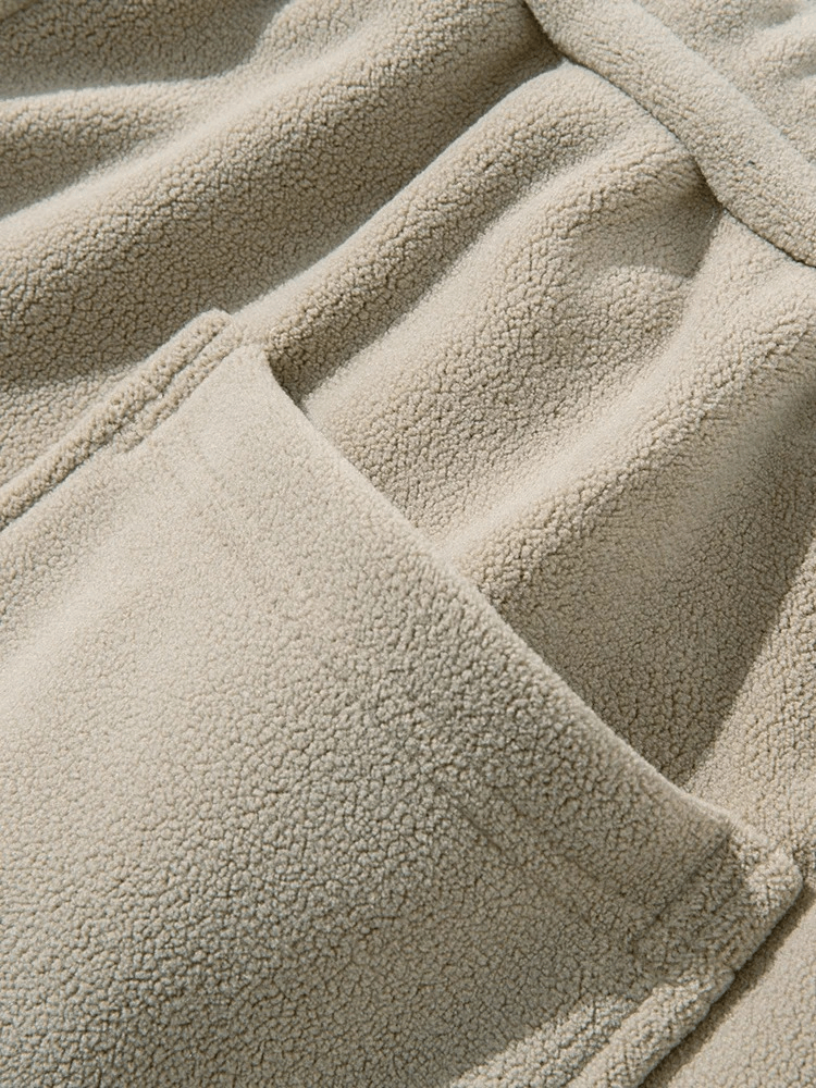 Close-up of beige fleece fabric with pocket detail on men's casual wide sweatpants.
