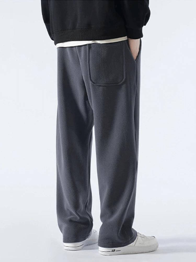 Back view of man wearing casual wide fleece sweatpants for men, showcasing loose fit, side pocket, and mid-rise waist style.