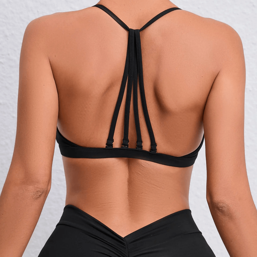 Back view of a chic multi-strap sports bra with stylish strappy design, perfect for active wear like yoga and running. Model showcasing unique back.