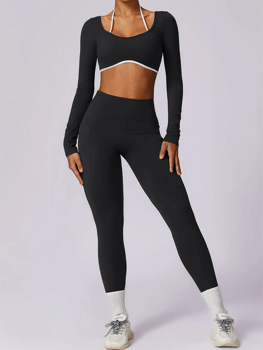 Woman wearing chic black nylon yoga set with crop top and high-waist leggings, perfect for fitness activities, breathable and quick drying.