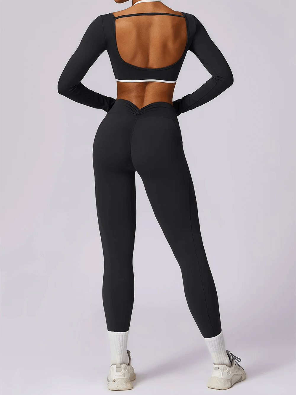 Alt Tag: Woman wearing a chic black nylon yoga set with long-sleeved crop top and high-waist leggings, ideal for all-season fitness activities.