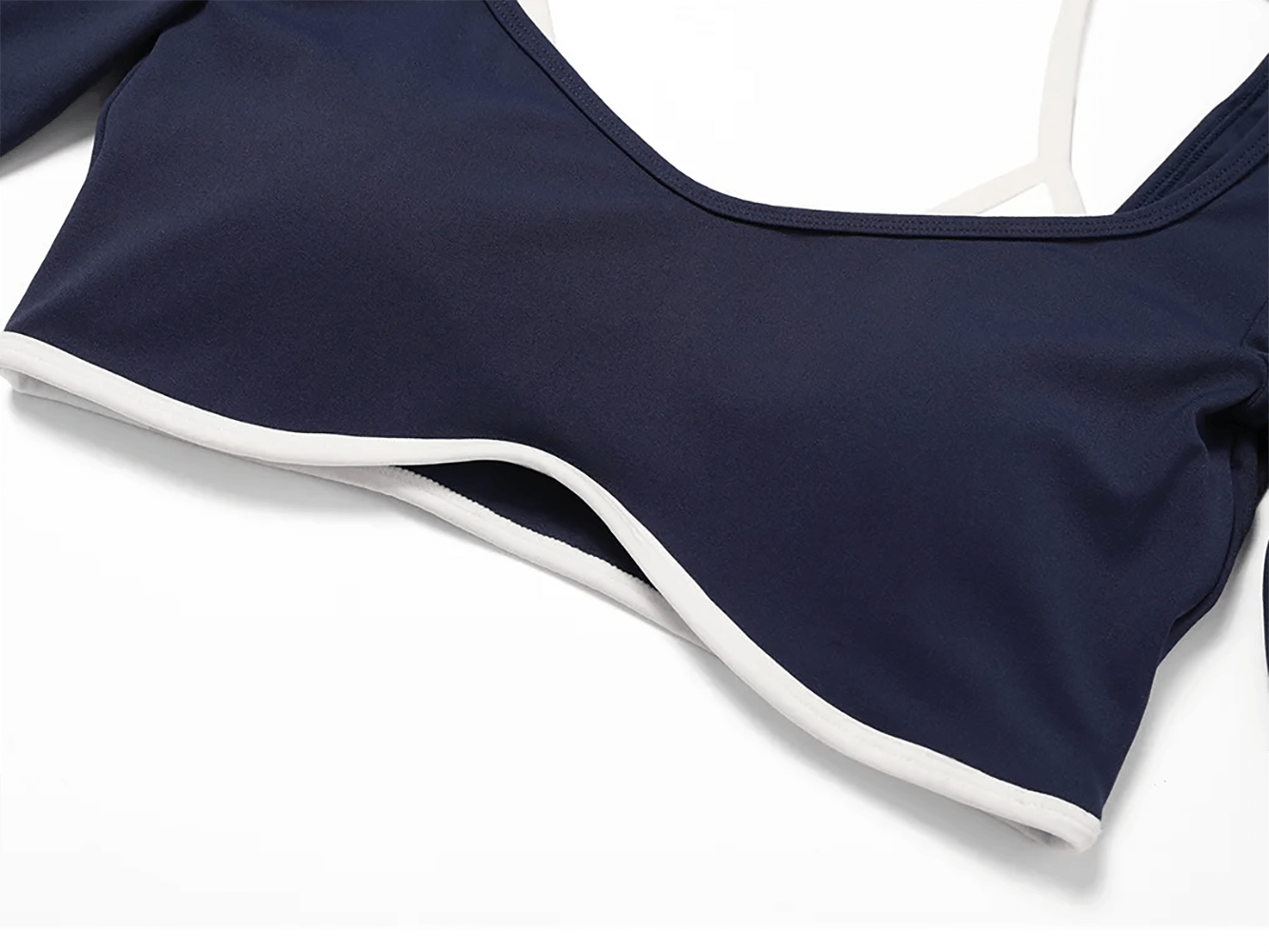 Close-up of navy blue nylon crop top from women's yoga set, featuring white trim and breathable fabric.