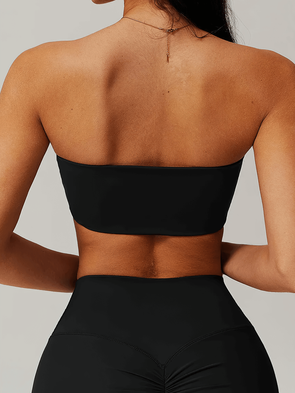 Back view of a sleek, neutral strapless bandeau crop top, highlighting minimalist design and secure fit.
