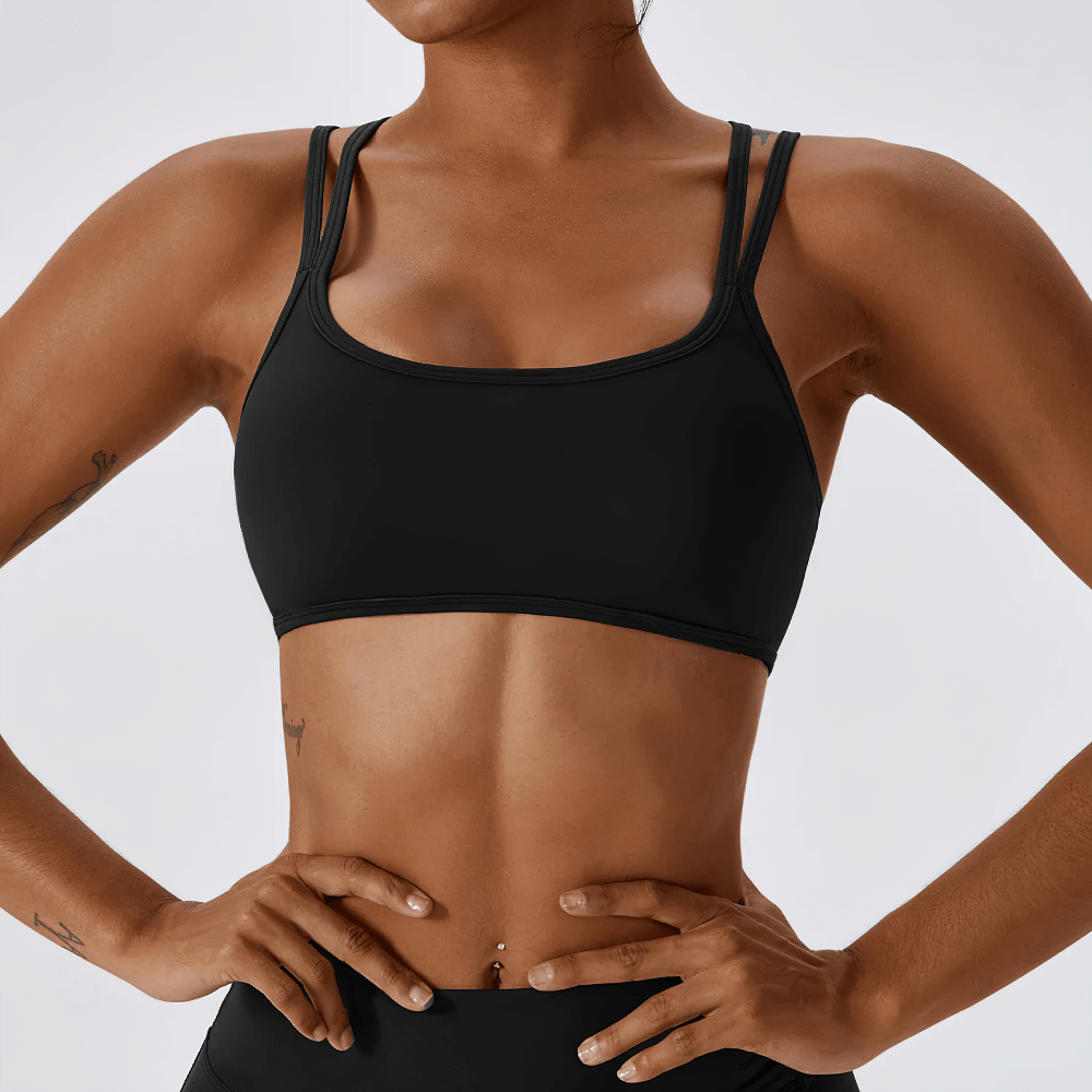 Chic black women's sports bra with cross-back design, perfect for active wear. Offers support and freedom of movement for workouts.