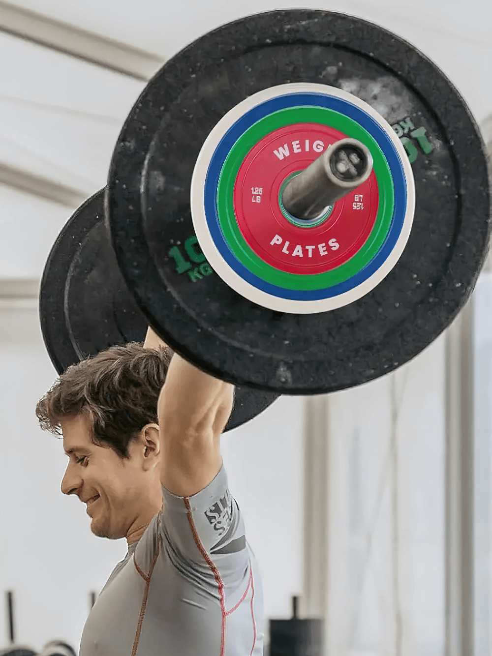 Man lifting barbell with color-coded weight plates for strength training
