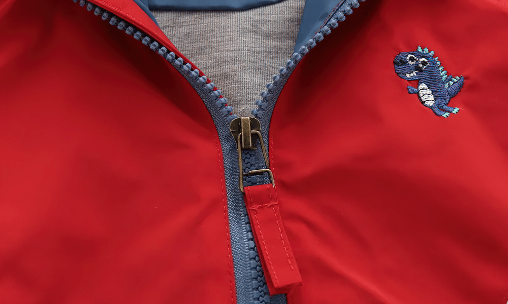 Close-up of Colorblock Hooded Windbreaker Jacket for Kids - SF3603 with zipper detail and playful dinosaur patch embroidery.