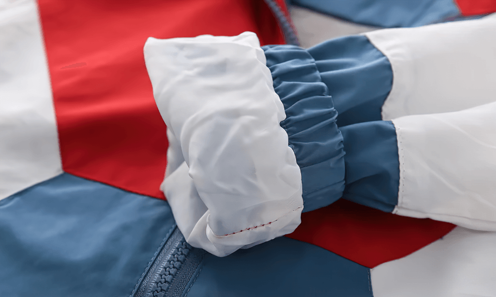 Close-up of the Colorblock Hooded Windbreaker Jacket for Kids - SF3603 showing elastic cuffs and multicolor patchwork design.