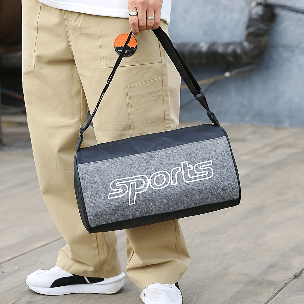 Person holding a colorblock shoulder bag with 'sports' letter pattern, ideal for gym use, featuring adjustable strap and spacious interior.