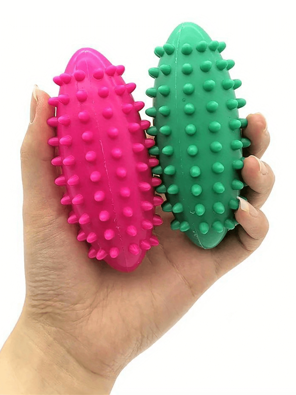 Hand holding vibrant pink and green spiked massage balls for muscle relief and fitness therapy.