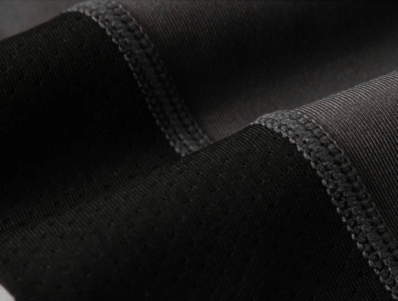 Close-up of black and gray dynamic patchwork pattern on men's compression running tights for performance and agility.