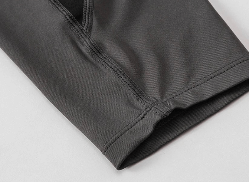 Close-up of dark gray compression men's running tights showcasing elastic patchwork design for agility and speed.