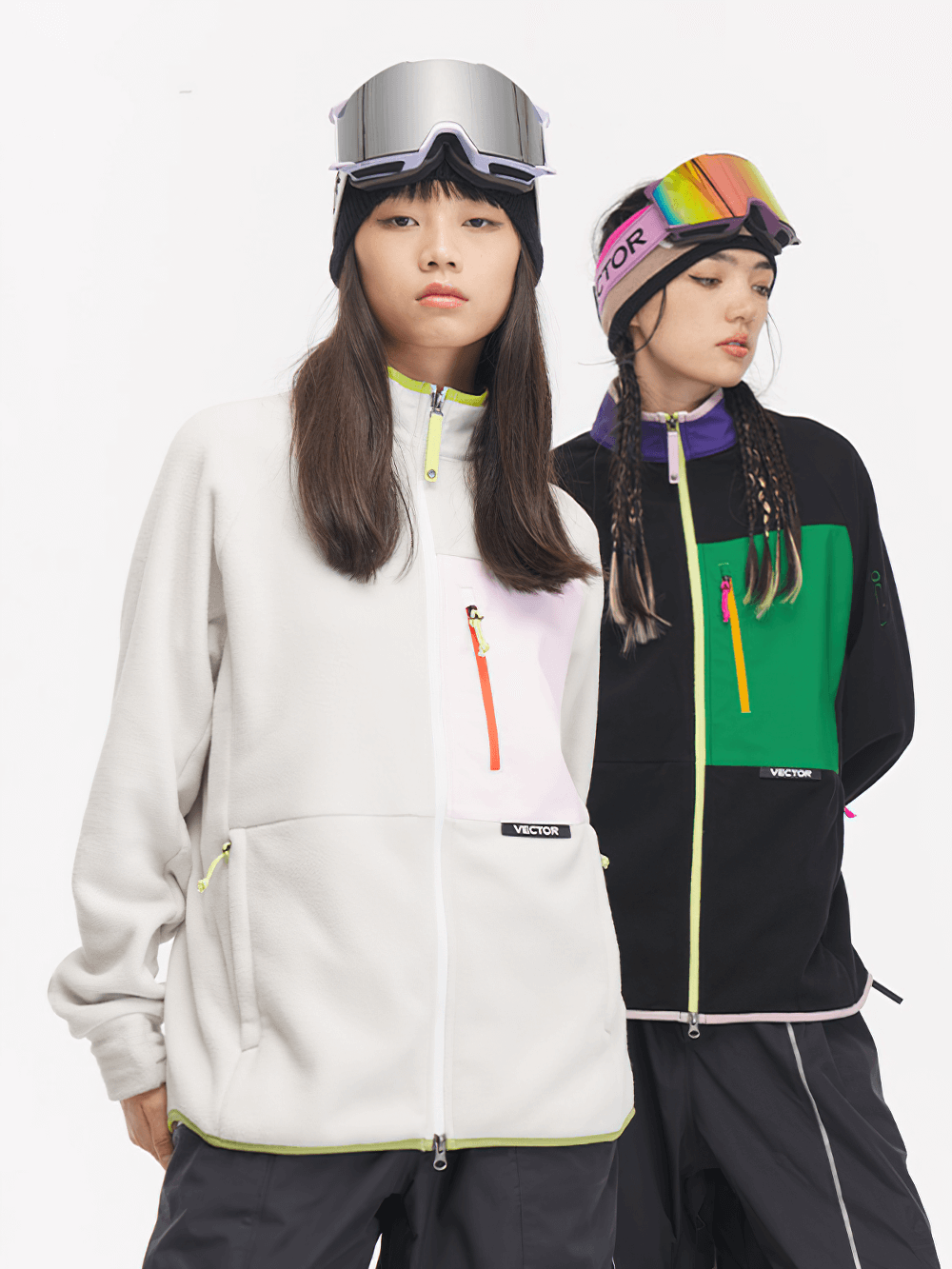 Two models wearing contrast full-zip fleece jackets for skiing, showcasing vibrant color block design with zip pockets.