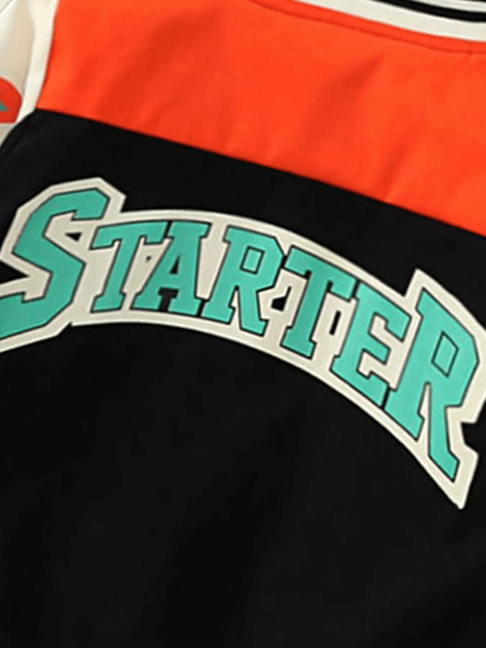 Close-up of Contrast Varsity Jacket with vibrant STARTER lettering in green and white on navy and orange fabric, stylish for kids.