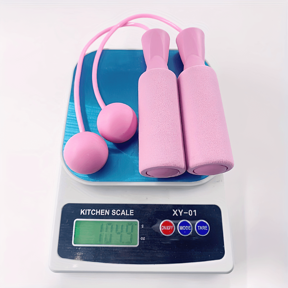 Pink cordless weighted jump rope with foam handles on a kitchen scale, weighing 114.0 ounces, ideal for cardio and fitness training.