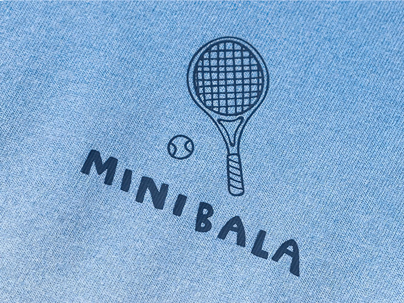 Close-up of a blue fabric with a tennis racket and ball design labeled 