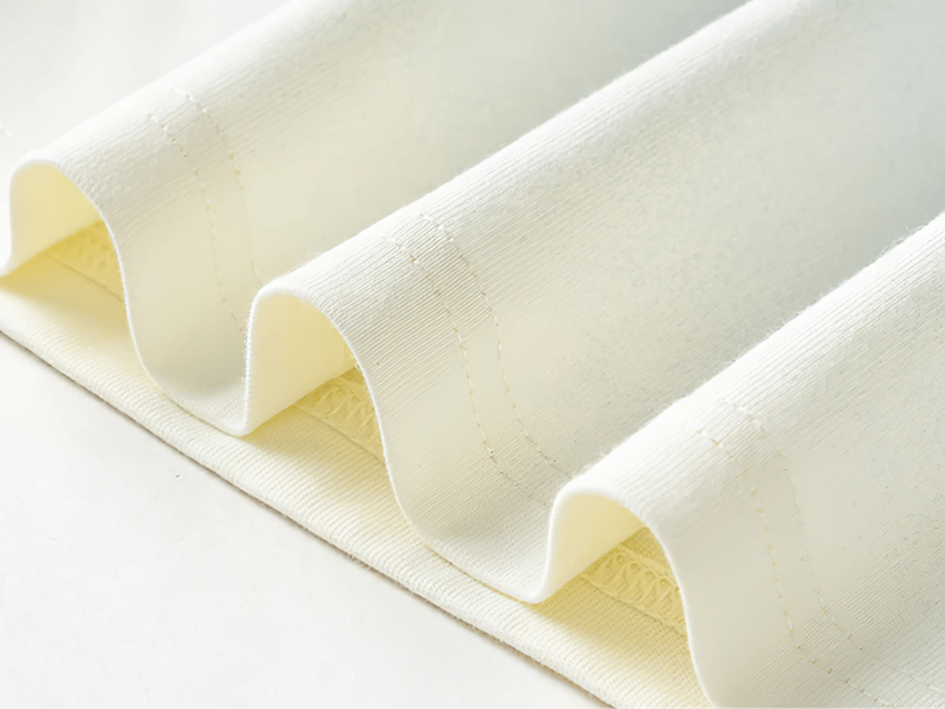 Close-up of white fabric texture with soft, wavy folds on a smooth surface