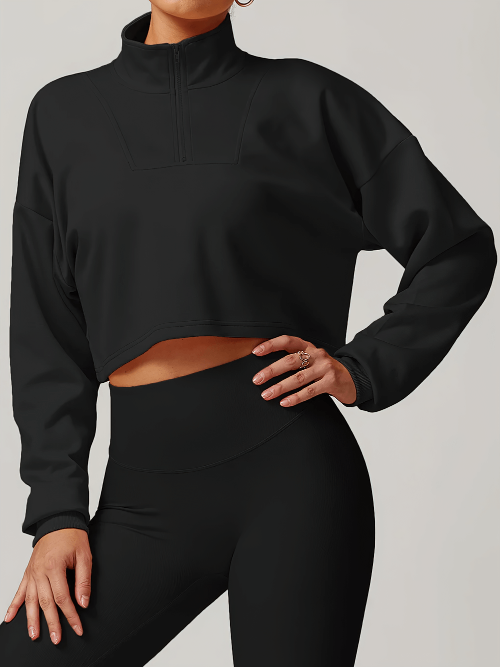 Woman wearing black cropped zip-up loose sweatshirt and leggings, showcasing athletic style and comfort for activewear or casual outings.