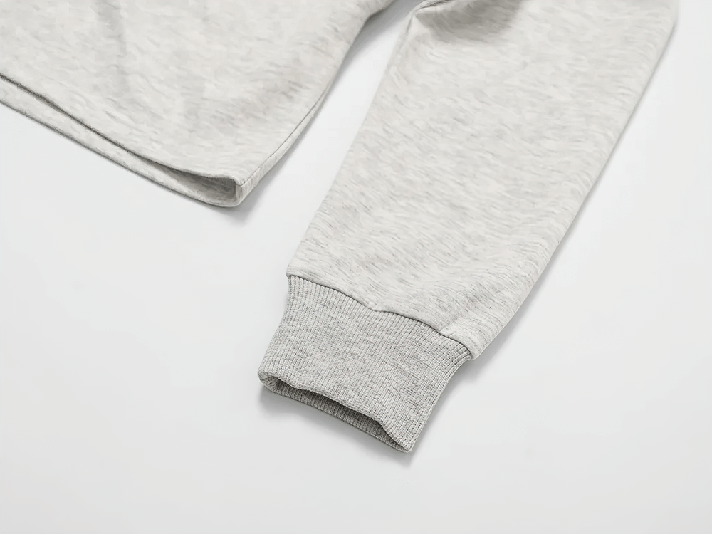 Close-up of the gray sleeve and ribbed cuff of a women's trendy cropped zip-up sweatshirt, emphasizing fabric details and modern design.
