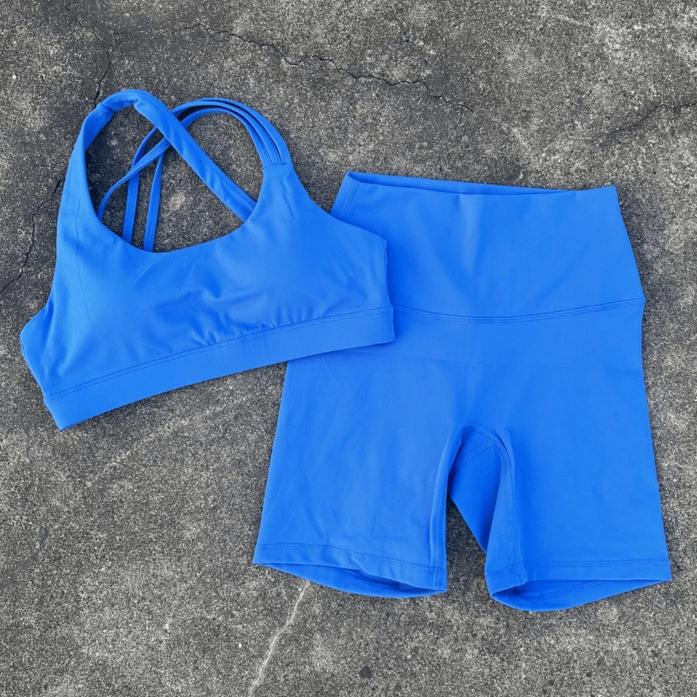 Alt Tag: Cross Back Yoga Bra and High Waist Gym Shorts Set - SF4355 blue cross-back sports bra with high-waist gym shorts on concrete