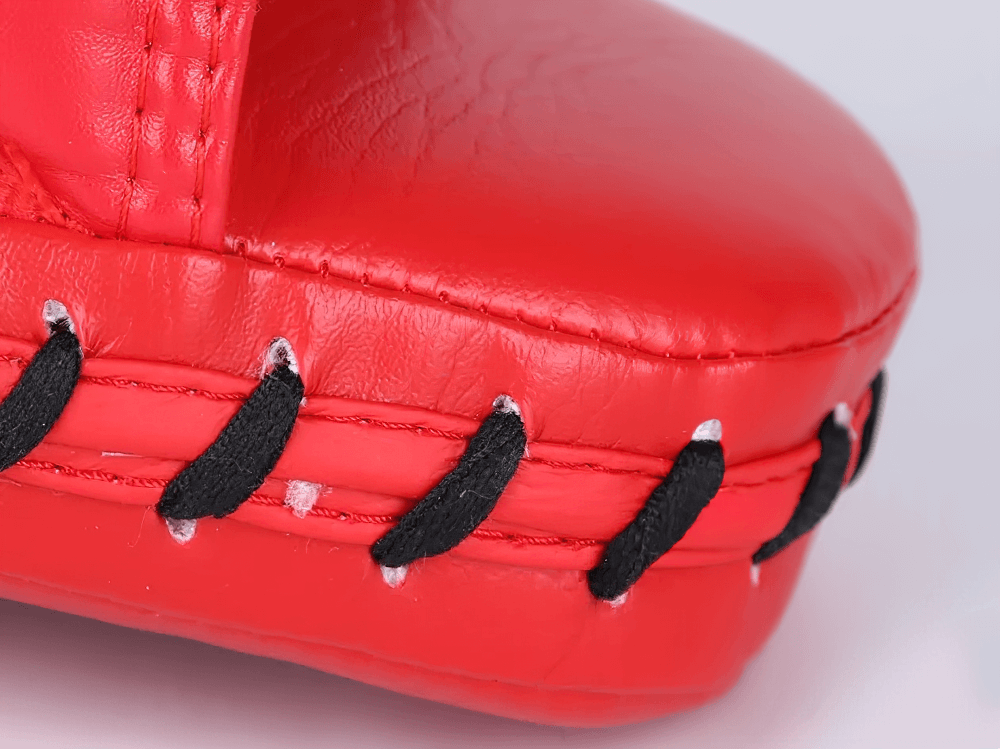 Close-up of a red curved boxing focus pad with durable stitched edges and PU leather, ideal for MMA, kickboxing, and martial arts training.
