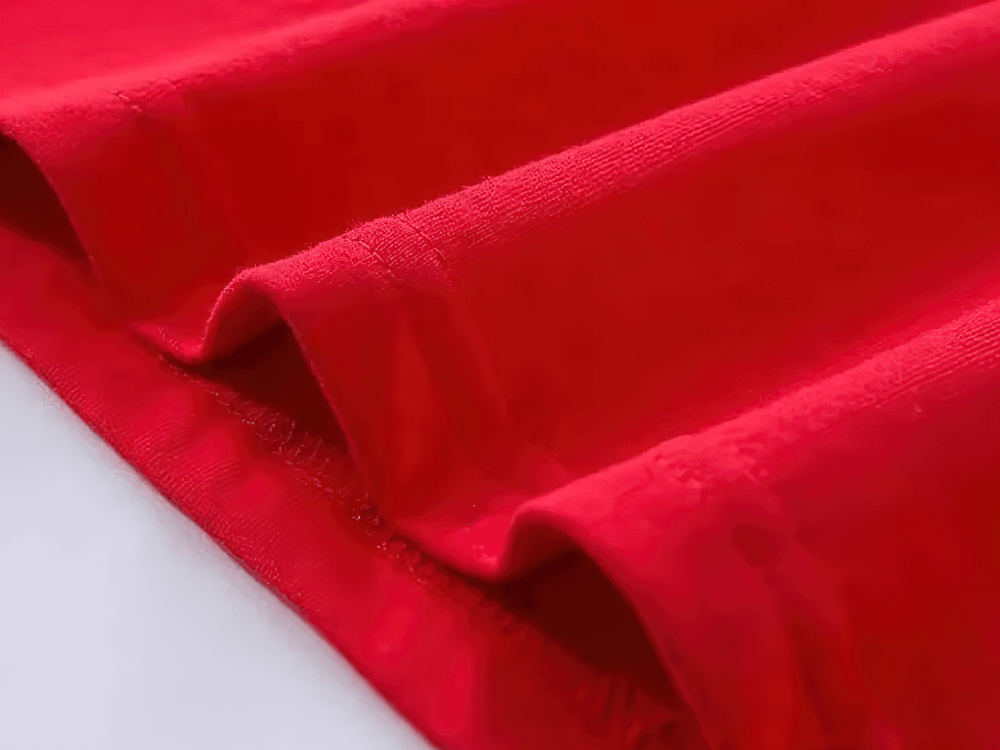 Close-up view of soft, breathable red fabric, showcasing texture and quality for kids' graphic tee shirts.