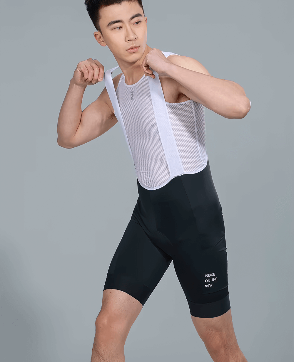 Man wearing black cycling bib shorts with padding and side pockets, showcasing flexibility and breathable mesh straps.