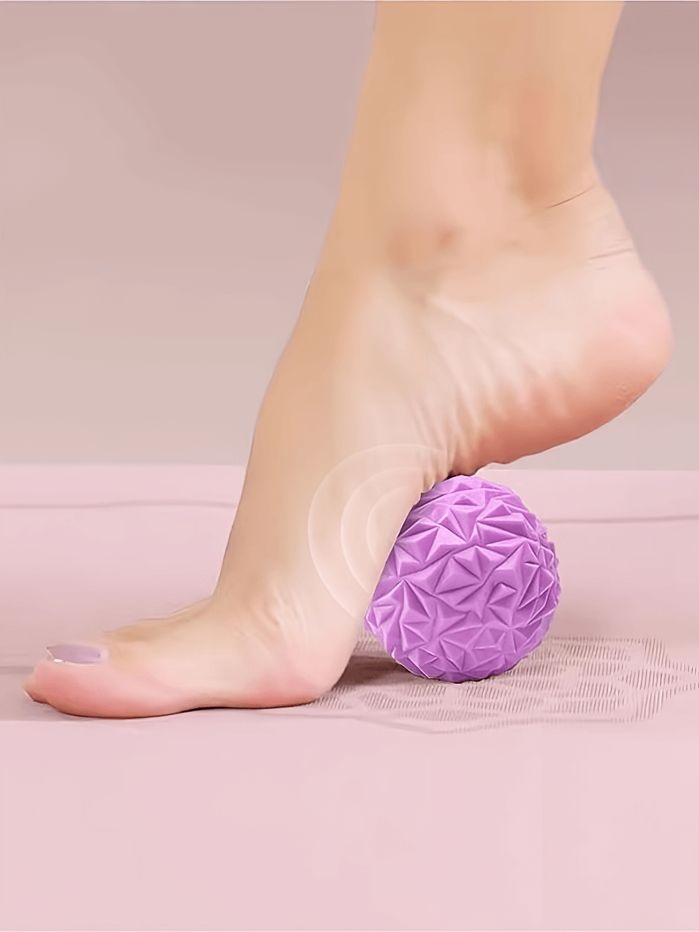 Foot using a purple textured massage ball for reflexology and myofascial release, enhancing circulation and muscle relief.