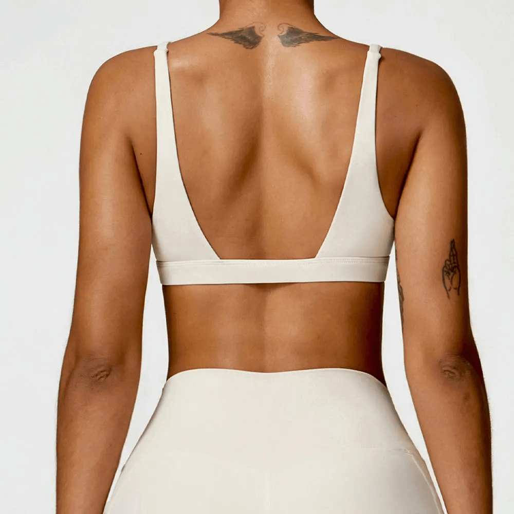 Back view of woman wearing deep V-neck padded sports bra for fitness, showcasing sleek design and comfortable fit.