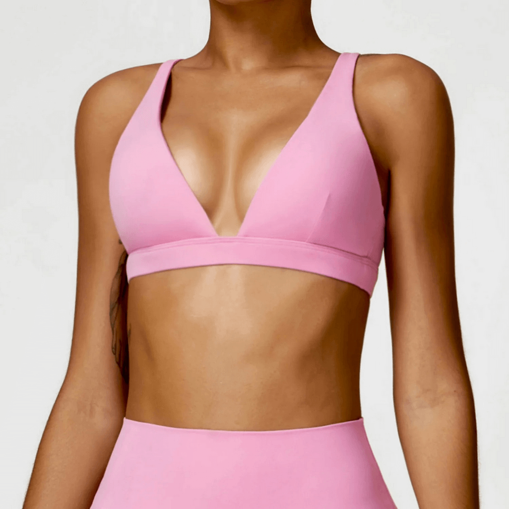 Woman wearing pink deep V-neck padded sports bra for fitness and yoga, designed for shockproof support and quick-dry comfort.