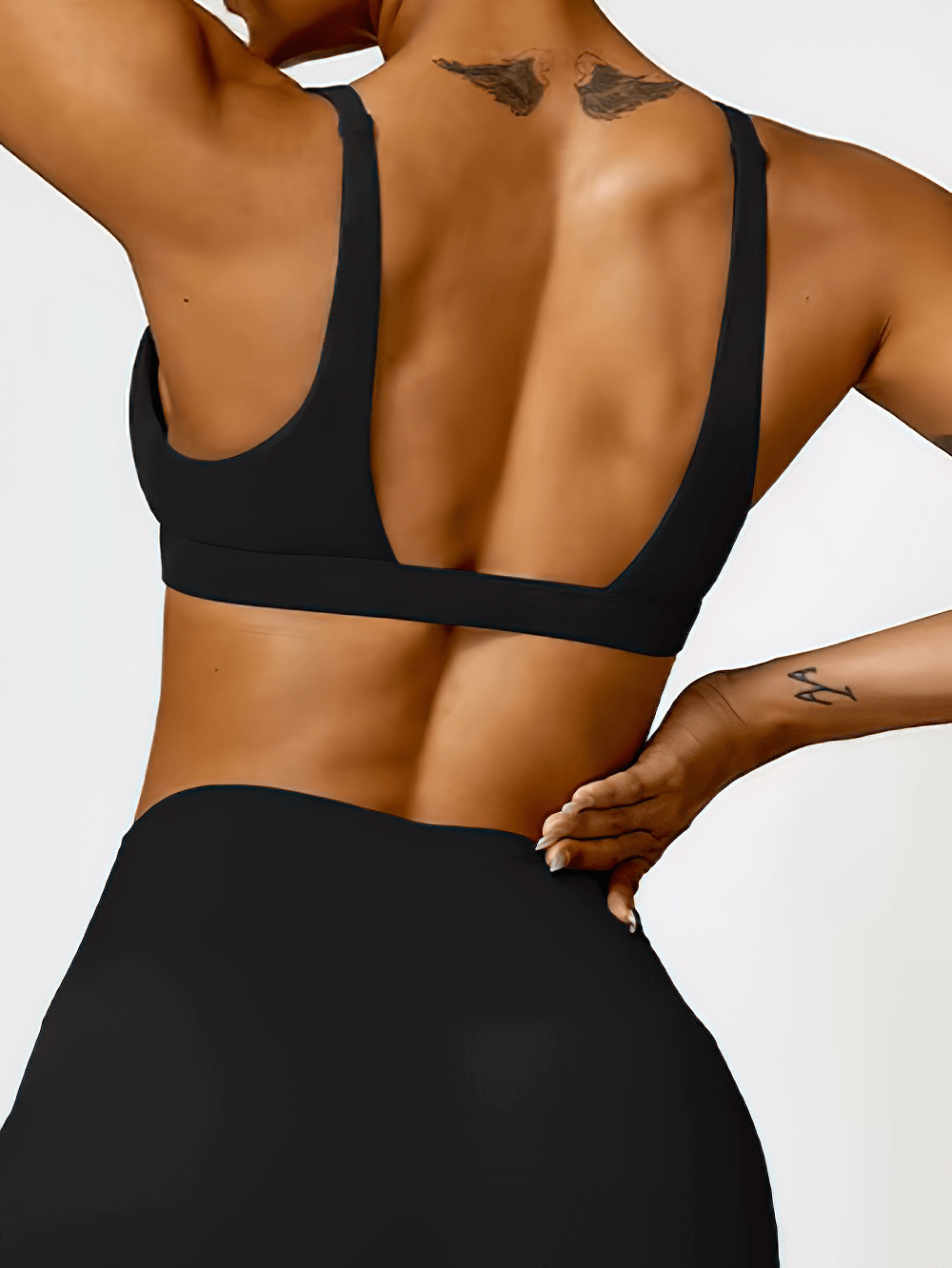 Back view of woman wearing black deep V-neck padded sports bra for fitness and yoga, showcasing sleek design and supportive fit.