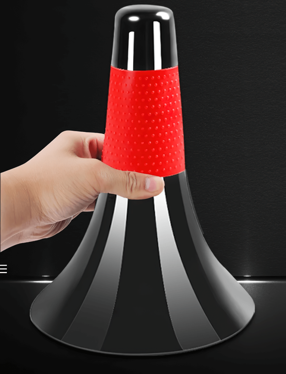 Close-up of a sleek black agility cone with a bright red band, held by a hand, ideal for football and basketball training drills.