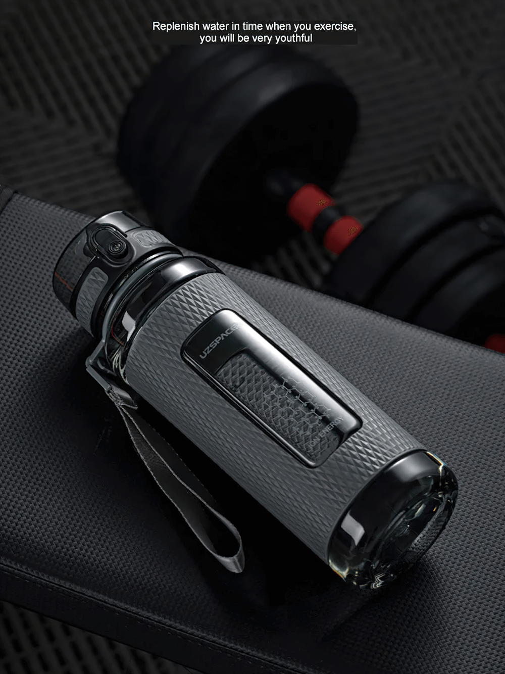 Grey leak-proof sports water bottle with handle and non-slip design on a gym bench.