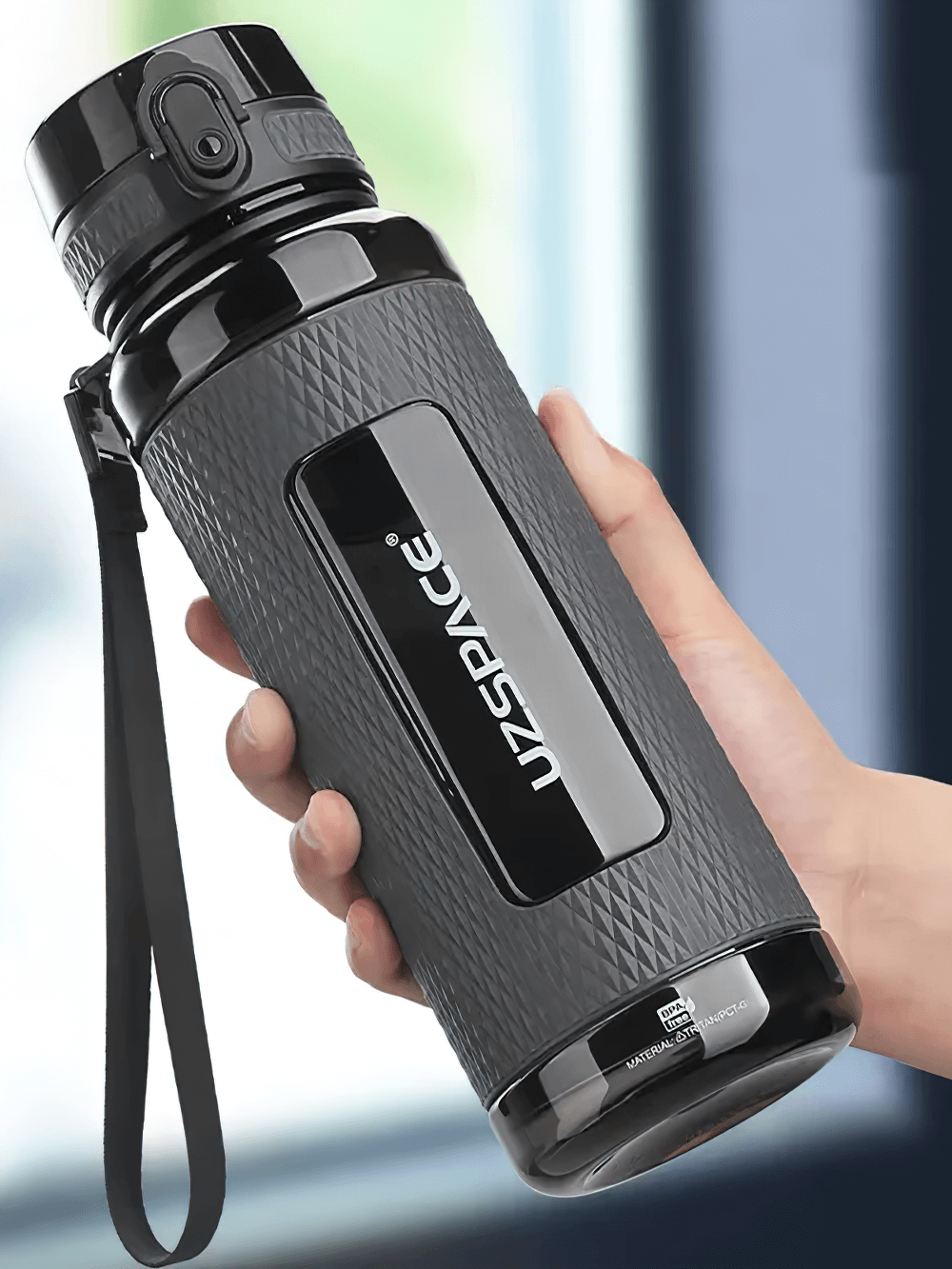 Hand holding a durable leak-proof sports water bottle with handle, featuring a non-slip texture and one-handed open design.