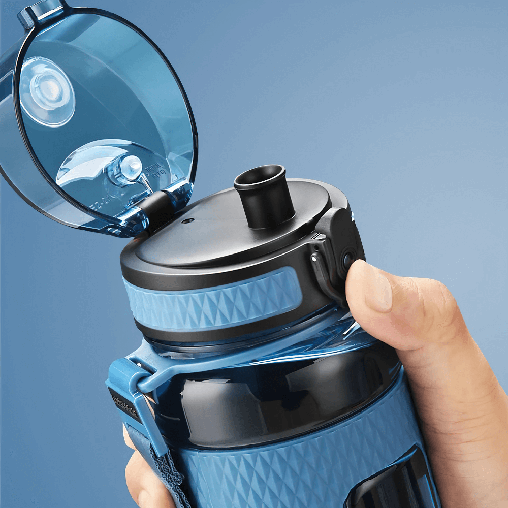 Close-up of a blue leak-proof Tritan sports water bottle being opened with one hand, highlighting its portable handle and non-slip texture.