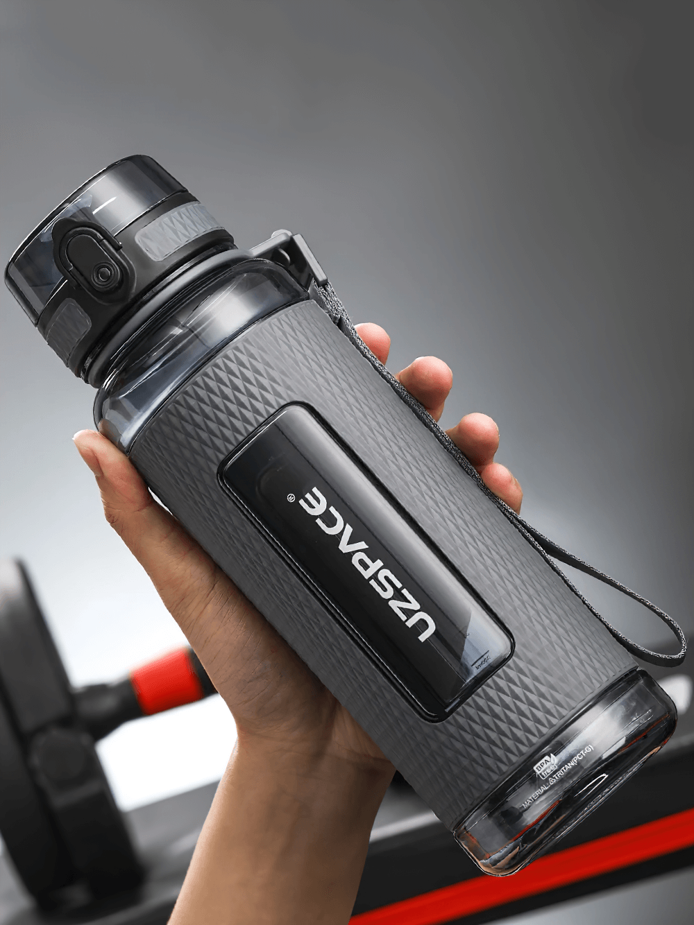 Person holding a durable leak-proof sports water bottle with handle and one-handed open feature, perfect for outdoor activities.