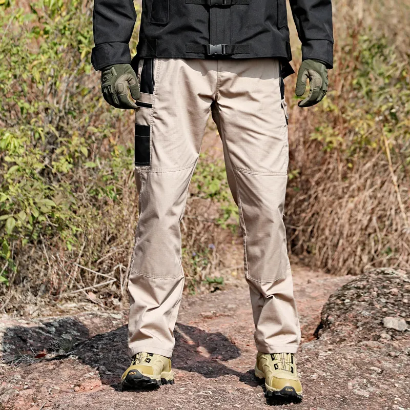 Man wearing durable trekking trousers with multiple pockets on rocky terrain.