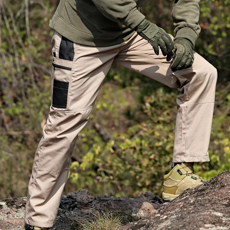 Person wearing durable trekking trousers with pockets on a rocky outdoor trail, showcasing reinforced knees and tactical design.