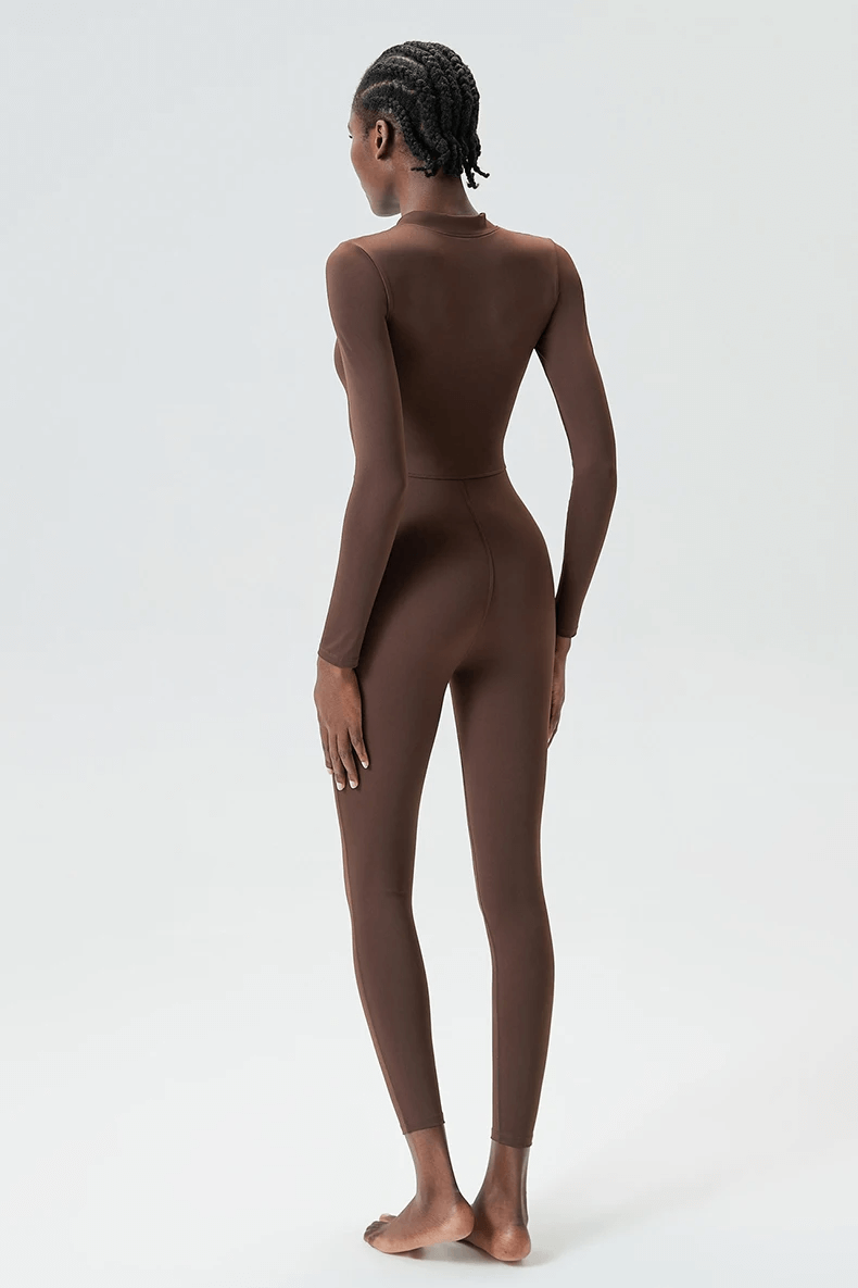 Woman wearing brown long-sleeve zip-front jumpsuit for yoga and gym, showcasing flexible fit and stylish activewear design.