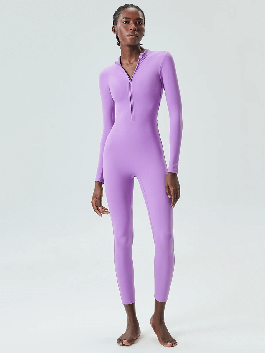 Woman wearing a purple zip-front long sleeve jumpsuit for yoga and gym, made of Nylon and Lycra, perfect for active wear.