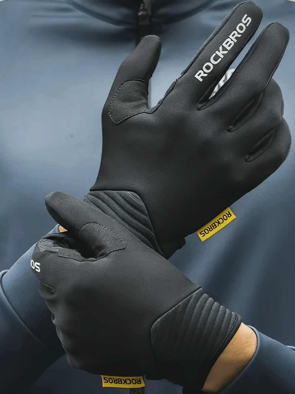 Cyclist wearing black elastic anti-slip full finger cycling gloves with touch screen functionality, brand logo visible.