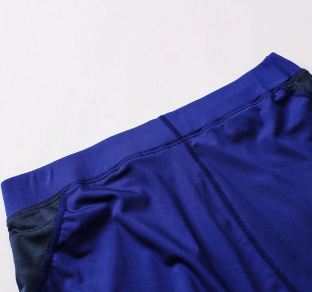Close-up of blue men's compression leggings with quick-drying fabric, showcasing elastic waistband and seamless design for comfort.