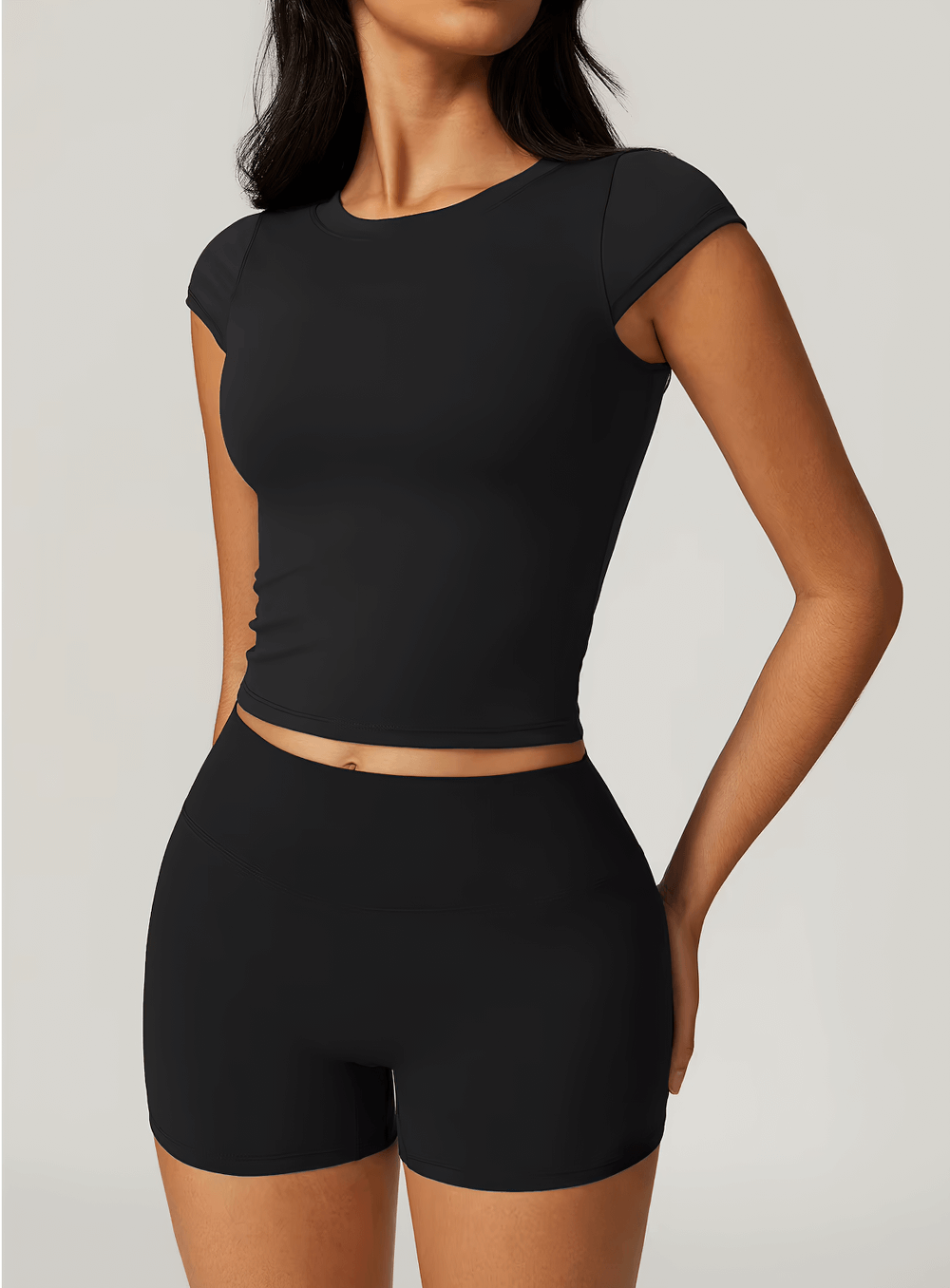 Woman wearing a black short sleeve elastic sport T-shirt, ideal for gym, yoga, and running. Anti-pilling and quick-dry fabric.
